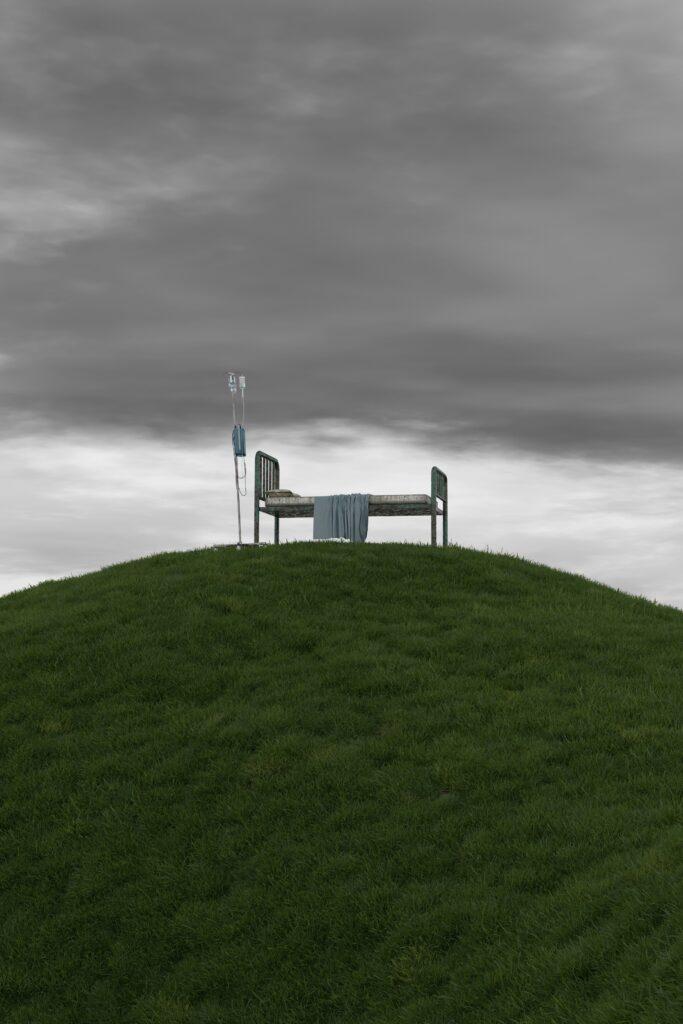 Lone hospital bed on a hill under a stormy sky – representing a turning point that never came in the binge drinking story
